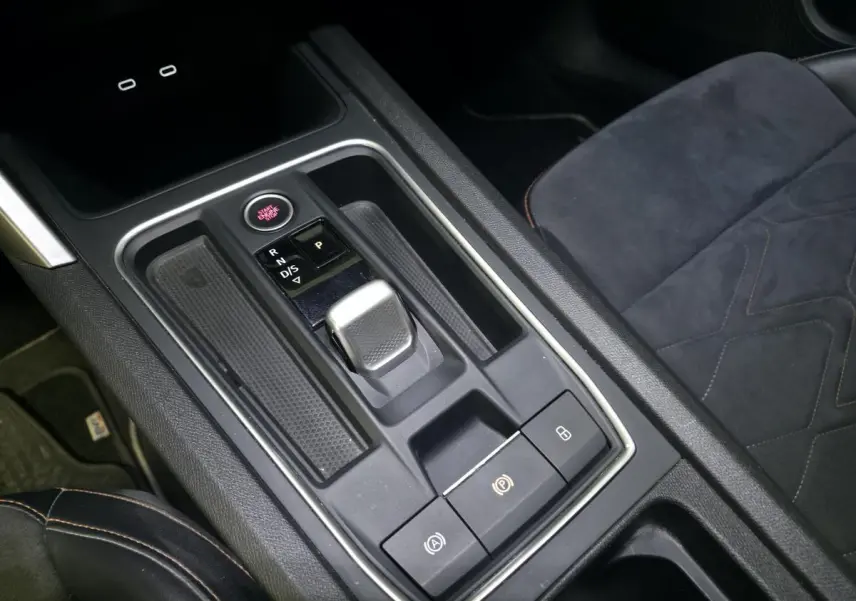 Gros plan sur la console centrale avec levier de boîte automatique et sièges sport en suédine noire du SEAT Leon Sportstourer.