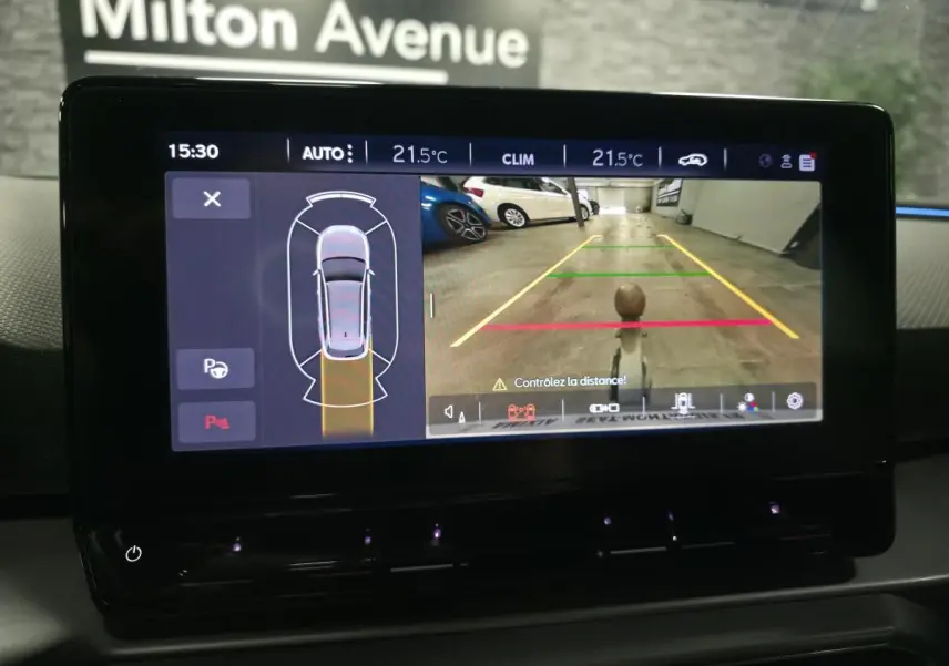 Écran tactile intérieur montrant la caméra de recul et l'aide au stationnement du SEAT Leon Sportstourer gris.