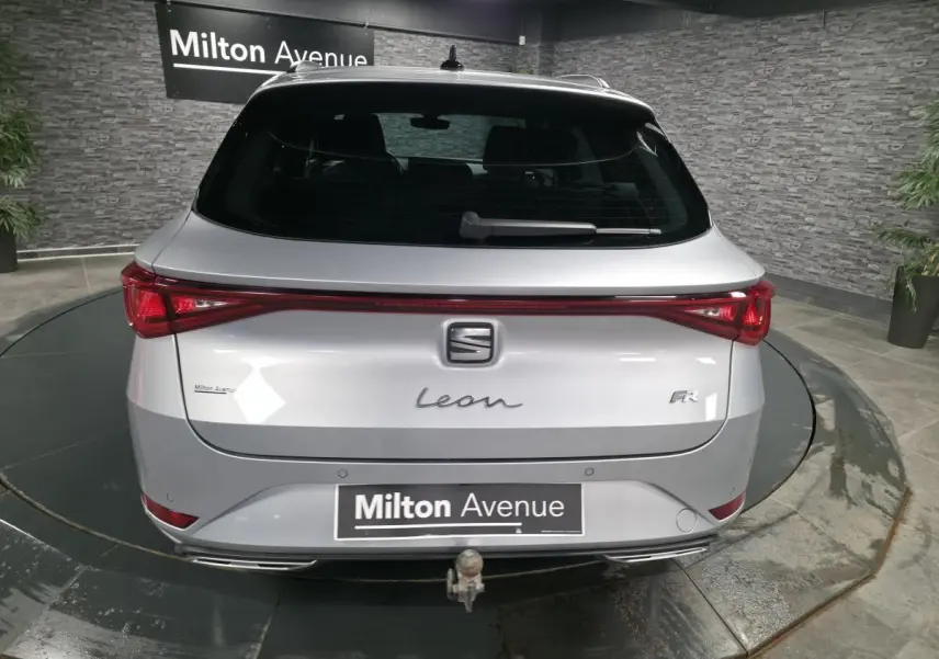 Vue arrière d'un SEAT Leon Sportstourer gris avec hayon électrique et crochet d'attelage escamotable visible.