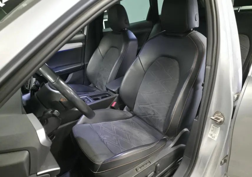 Vue intérieure côté conducteur d'une SEAT Leon Sportstourer gris urbain, sièges sport en suédine noire avec surpiqûres rouges.