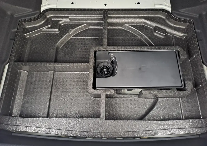 Compartiment de rangement en mousse noire dans le coffre d'une Peugeot 308 blanc Okenite, vue de dessus sans chargement.