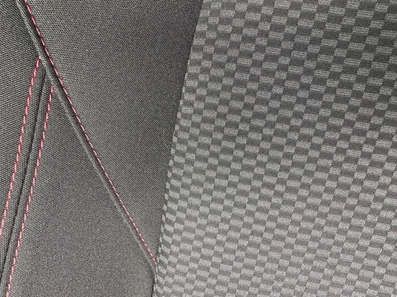 Détail du tissu de siège avec motif damier gris et coutures rouges sur Ford Puma 2024 Noir Agate Métallisée.