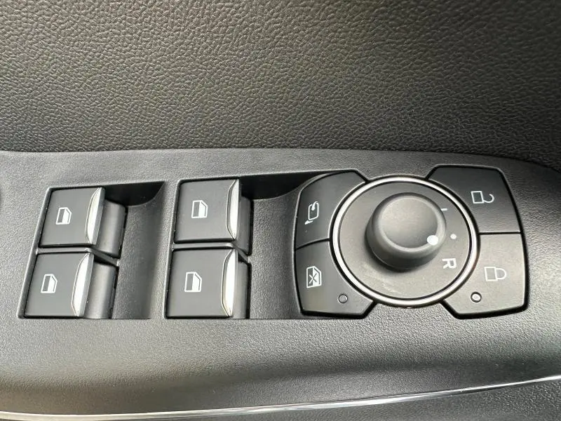 Gros plan sur les commandes de lève-vitres et réglage des rétroviseurs côté conducteur du Ford Puma 2024.