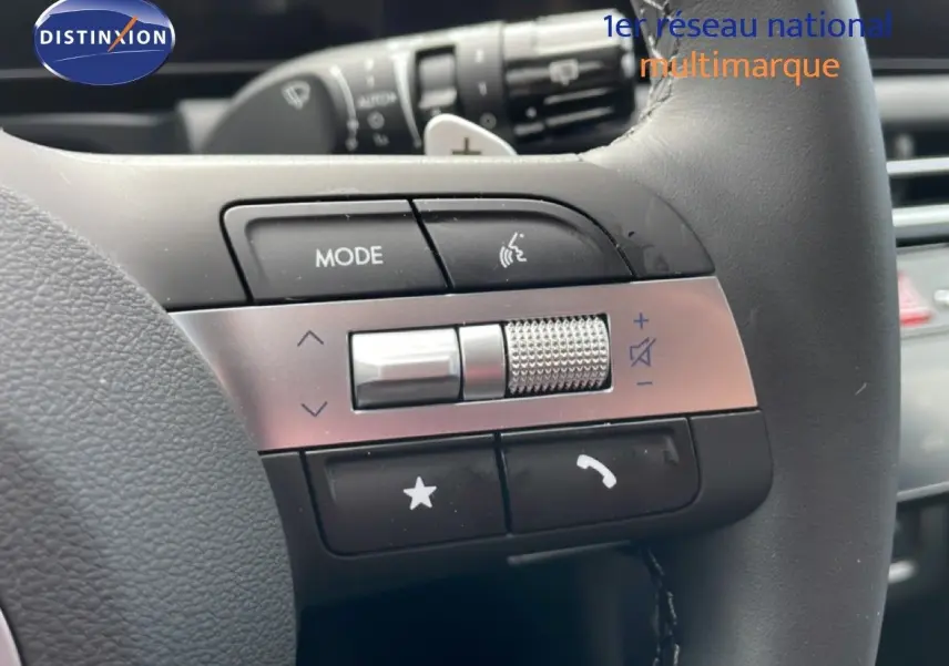 Gros plan sur les commandes du volant cuir noir du Hyundai Tucson blanc Atlas, version hybride 2026.