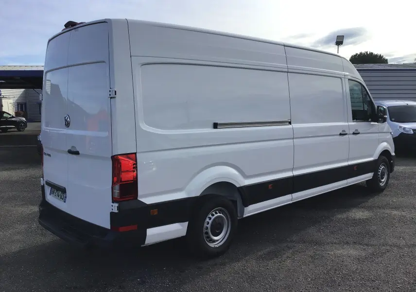 Volkswagen Crafter fourgon blanc en vue 3/4 arrière droit, soulignant sa grande taille et ses feux arrière rouges.