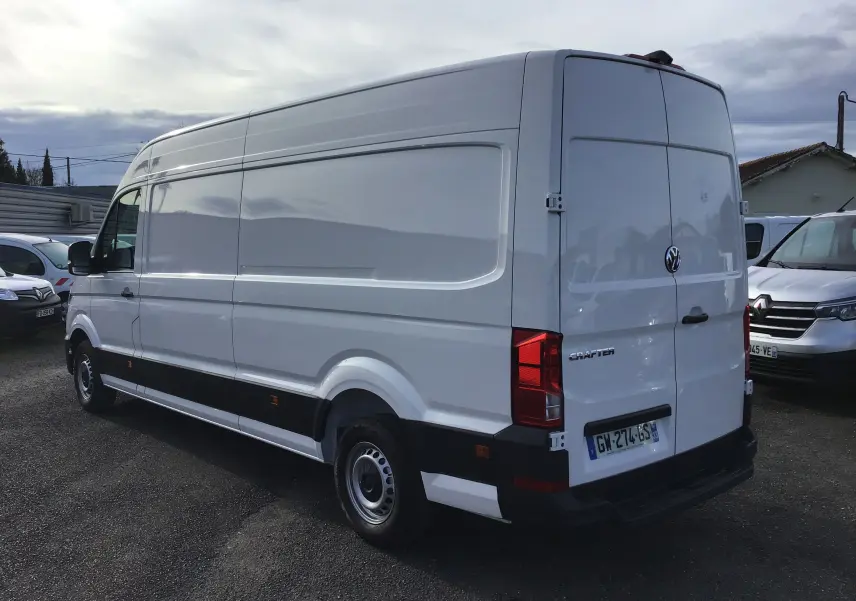Vue 3/4 arrière droite d’un Volkswagen Crafter blanc 2024, fourgon utilitaire avec porte arrière fermée et feux rouges visibles.