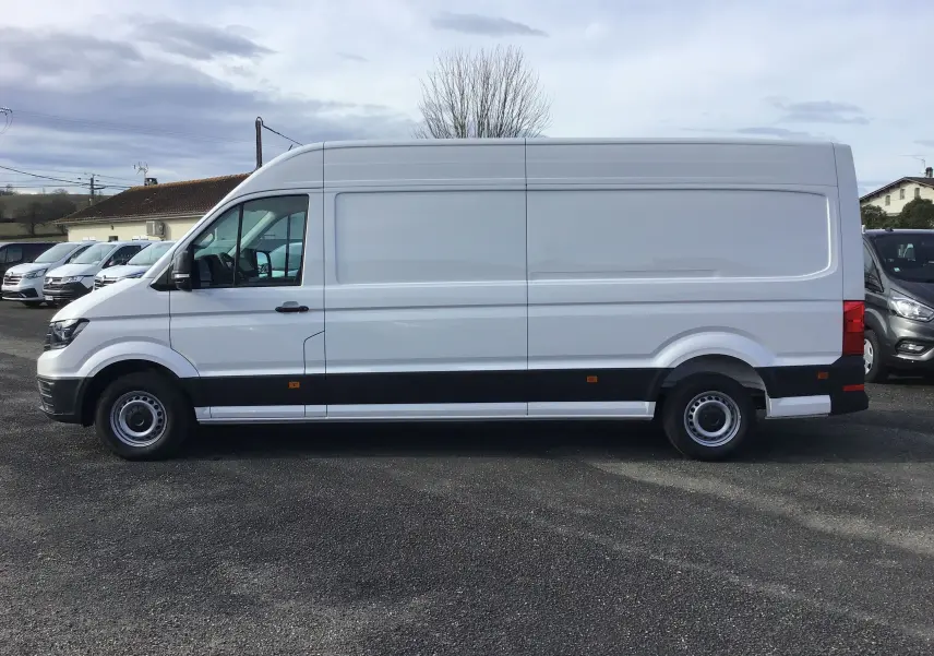 Profil côté gauche d'un utilitaire Volkswagen Crafter blanc 2024, version L4H3, avec bande noire basse et roues acier.