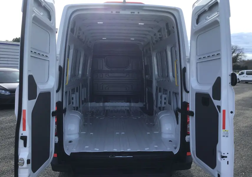 Vue arrière du Volkswagen Crafter Fourgon blanc 2024 avec portes ouvertes montrant la grande capacité de chargement vide.