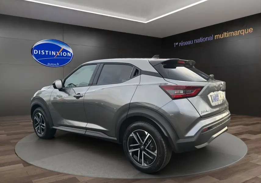 Vue 3/4 arrière droite d'un Nissan Juke gris squale avec jantes alliage et toit noir en showroom.