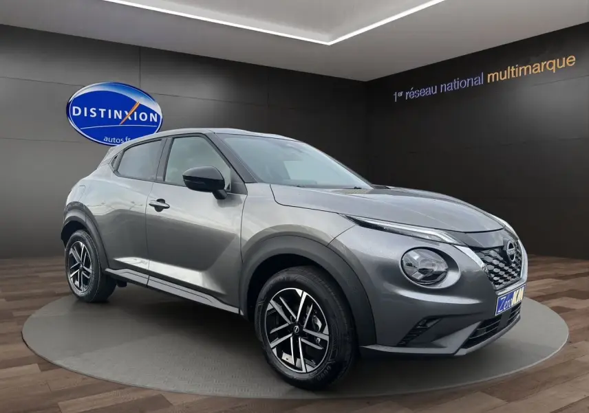 Nissan Juke Full Hybrid gris squale en 3/4 avant droit, avec jantes alliage noires et calandre distinctive.