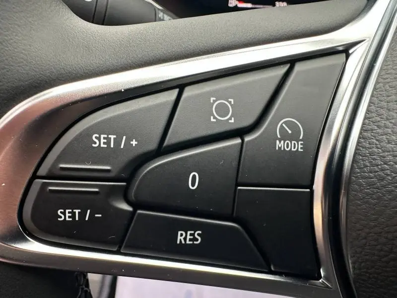 Gros plan sur les commandes au volant du Renault Captur 2025, boutons de régulateur et mode en plastique noir.