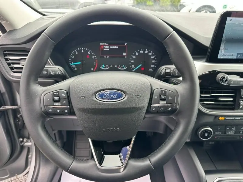 Vue intérieure centrée sur le volant cuir multifonction du Ford Kuga gris, avec tableau de bord et écran tactile visibles.