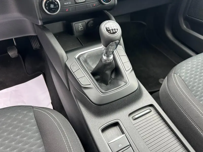 Gros plan sur la console centrale du Ford Kuga 2024 avec levier de vitesse manuel et sièges tissu noir.