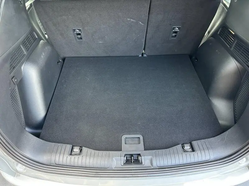 Coffre ouvert du Ford Kuga 2024 gris Solar, vue plongeante sur le plancher de coffre propre et spacieux.