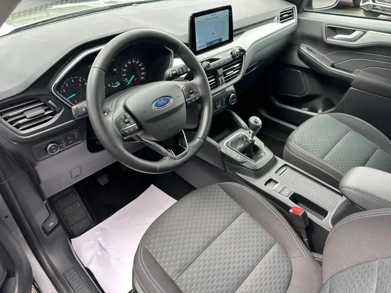 Intérieur avant droit du Ford Kuga 1.5 EcoBoost 2024 avec volant cuir multifonction et boîte manuelle, sièges tissu noir.