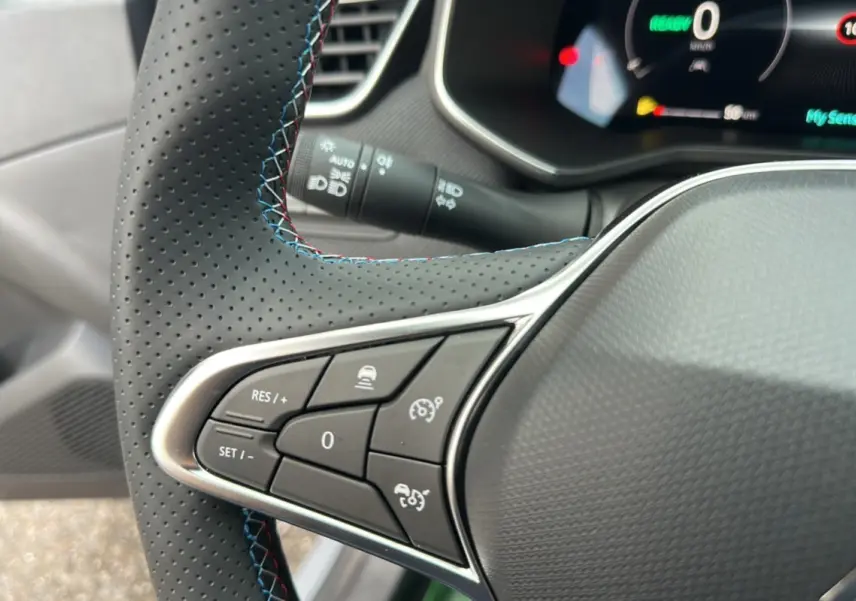 Gros plan sur les commandes au volant cuir perforé avec surpiqûres bleues de la Renault Clio V E-Tech 145 Esprit Alpine Bose.