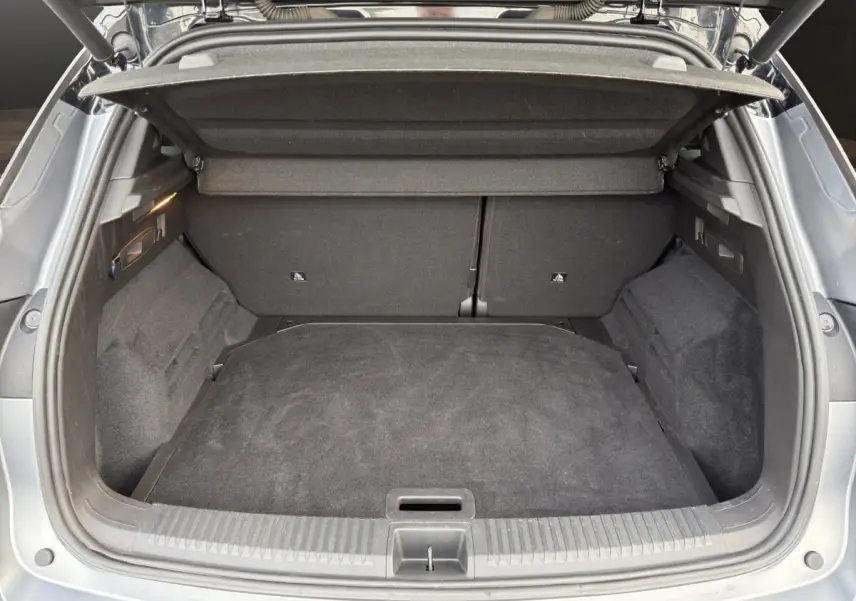 Coffre ouvert vu de l'arrière d'un Renault Austral gris foncé, montrant l'espace de chargement vide et la tablette de coffre.
