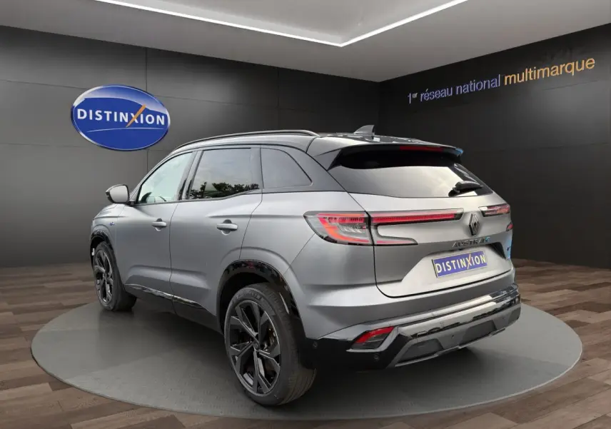 Vue 3/4 arrière droite d'un Renault Austral gris foncé avec feux arrière LED et jantes noires en showroom.