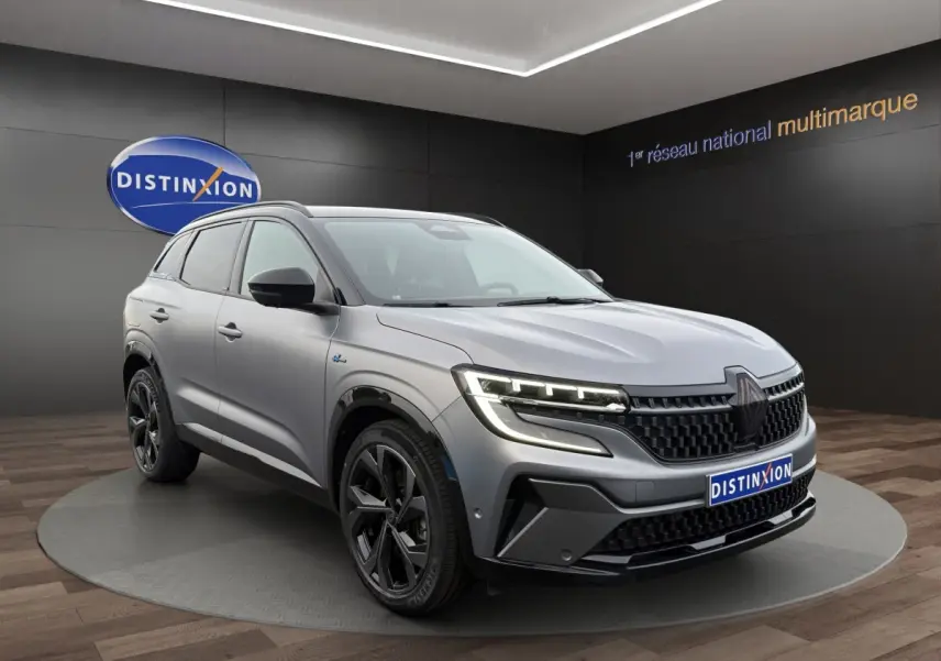 Renault Austral gris foncé en 3/4 avant droit, avec calandre noire et phares LED distinctifs allumés.