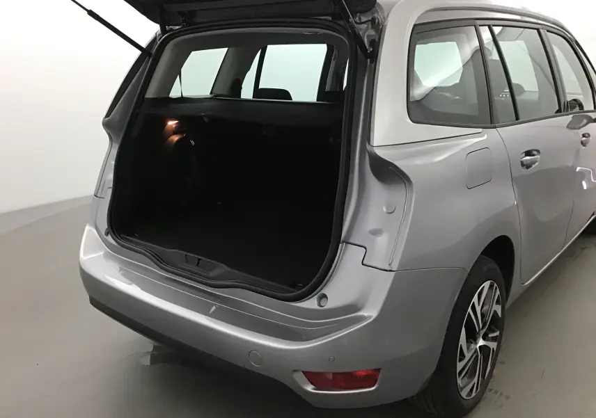 Vue arrière côté droit d'un Citroën Grand C4 Spacetourer gris Artense avec coffre ouvert et intérieur sombre visible.