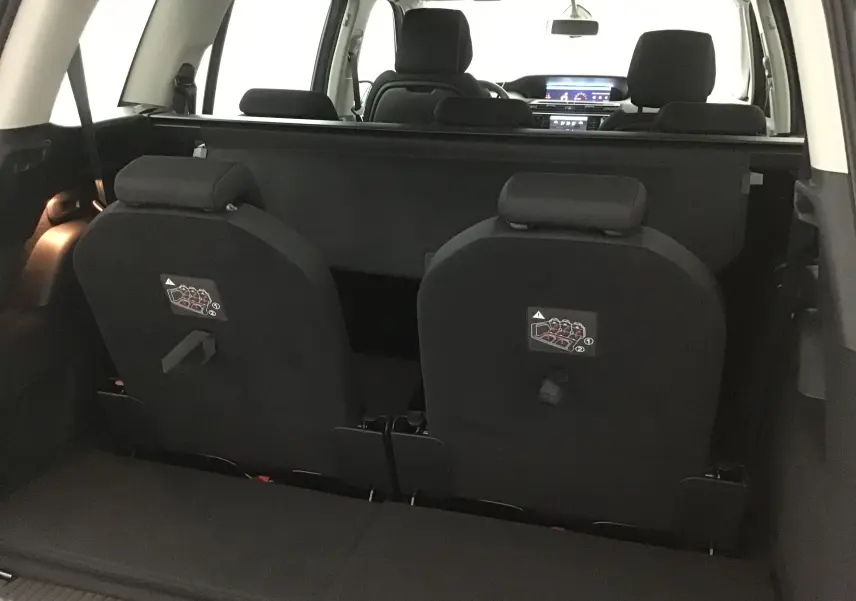 Vue intérieure arrière du Citroën Grand C4 Spacetourer gris, montrant les sièges rabattus et l'habitacle avant lumineux.