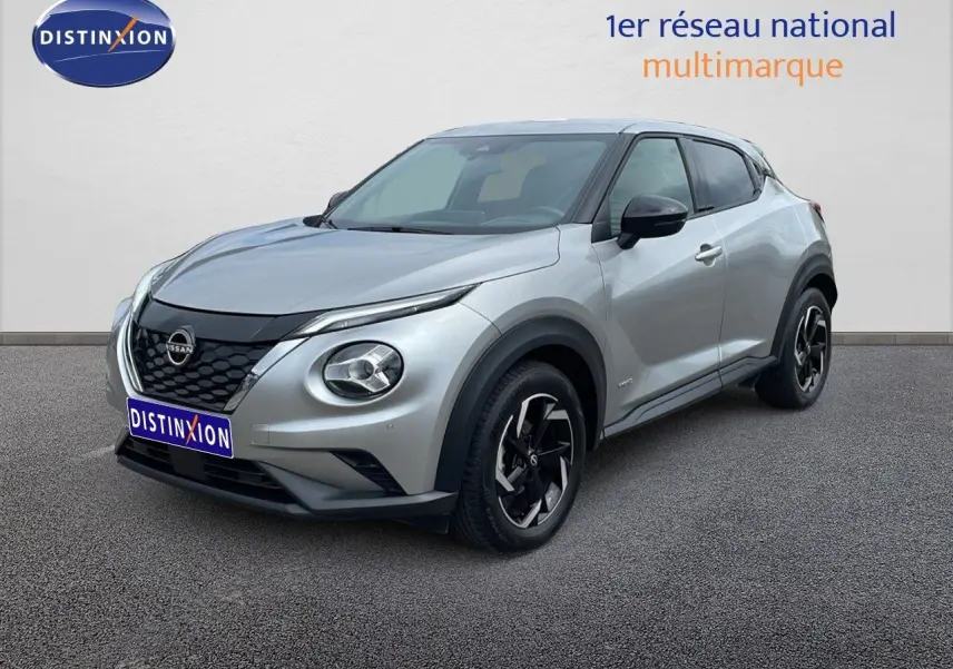 Nissan Juke Hybrid gris perle métal en 3/4 avant droit, avec jantes noires et détails noirs contrastants.