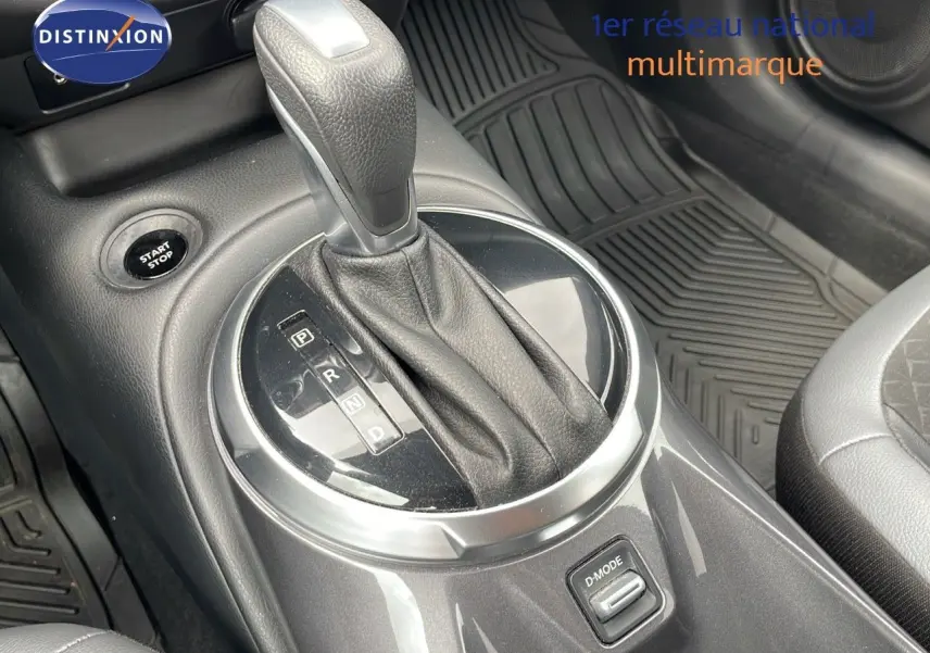 Le levier de vitesse automatique du Nissan Juke Hybrid gris perle, avec bouton start/stop et tapis caoutchouc visible.