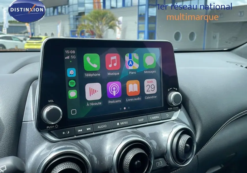 Écran tactile central avec Apple CarPlay dans l'habitacle d'un Nissan Juke Hybrid gris perle 2023.