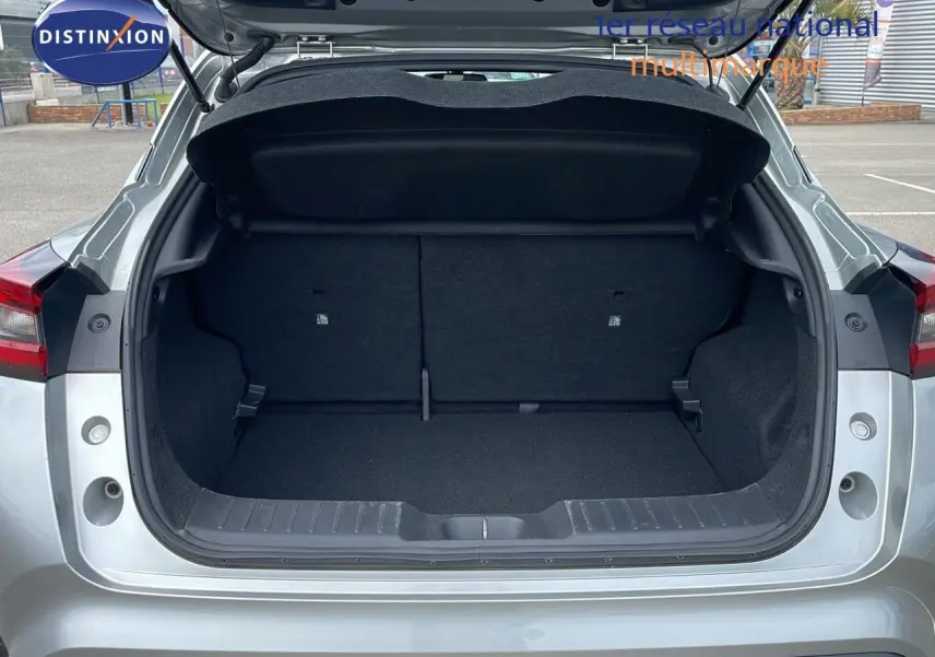 Coffre ouvert d'un Nissan Juke Hybrid gris perle métal, vue arrière mettant en valeur l'espace de chargement vide.