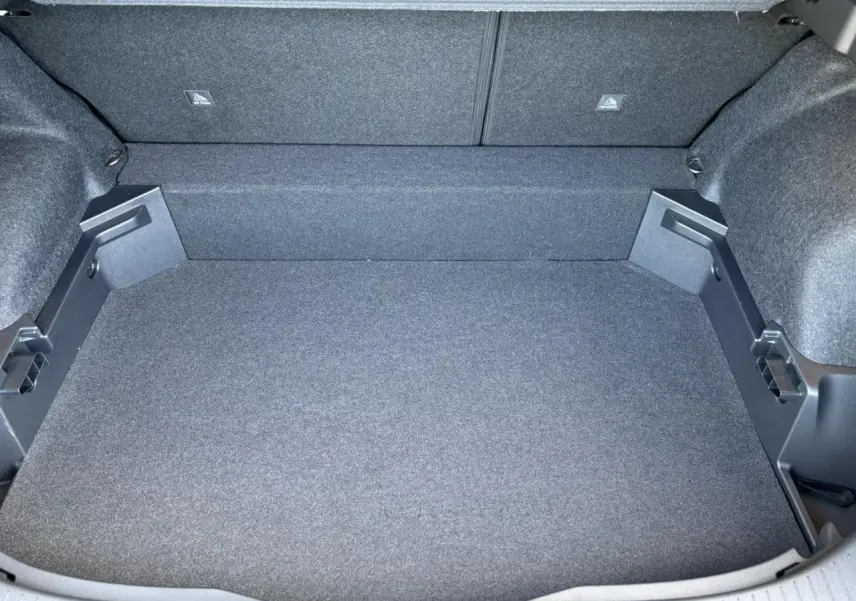 Vue plongeante sur le coffre spacieux et vide du Nissan Qashqai blanc nacré, revêtement gris foncé uniforme.