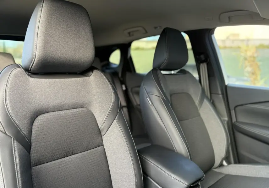 Vue intérieure rapprochée des sièges avant gris et noirs du Nissan Qashqai III e-Power 2025, avec accoudoir central.