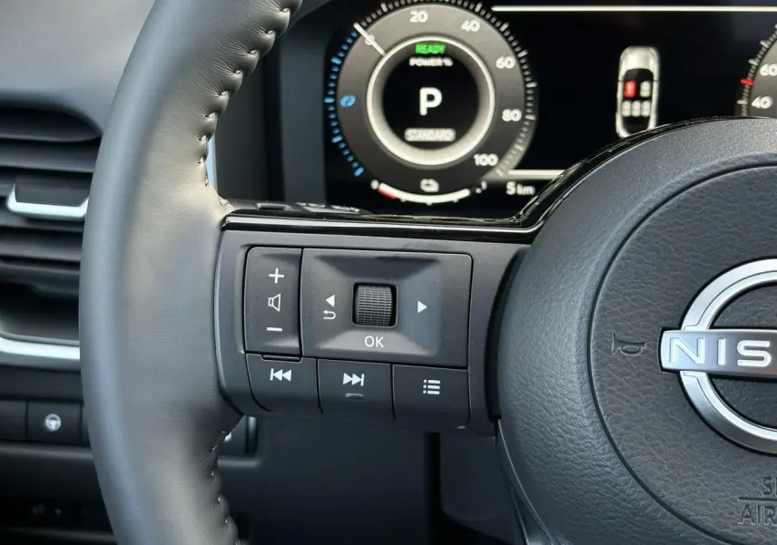 Gros plan sur le volant cuir noir du Nissan Qashqai 2025 avec commandes multifonctions et tableau de bord numérique.