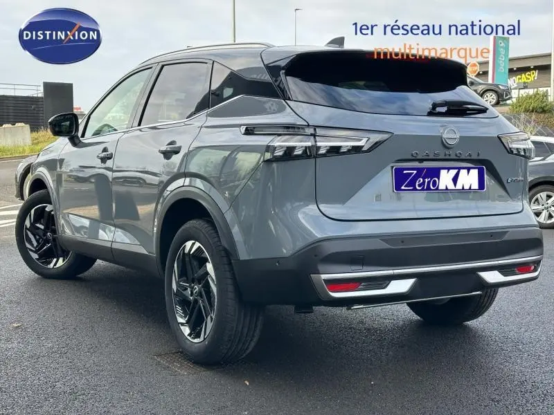 Vue 3/4 arrière droite du Nissan Qashqai Hybrid e-POWER 2025 en gris Argile avec jantes noires et feux LED distinctifs.