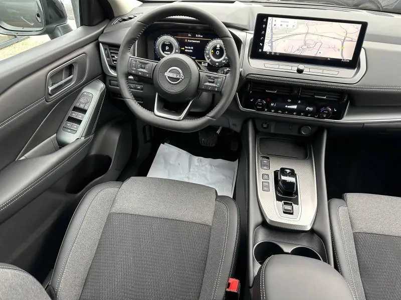Vue intérieure du poste de conduite du Nissan Qashqai Hybrid e-POWER 2025, avec tableau de bord numérique et écran tactile central.