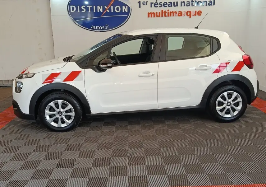 Vue de profil côté gauche d'une Citroën C3 blanche 2021 avec bandes rouges diagonales sur ailes avant et arrière.