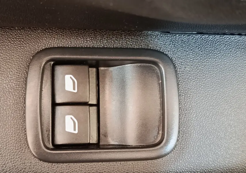 Gros plan sur les boutons de commande des vitres électriques côté conducteur d’une Citroën C3 blanche.