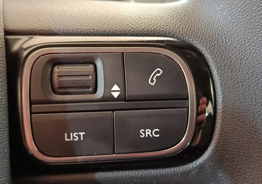 Gros plan sur les commandes noires du volant multifonctions du Citroën C3 blanc, version BlueHDi 100 S&S BVM Feel.