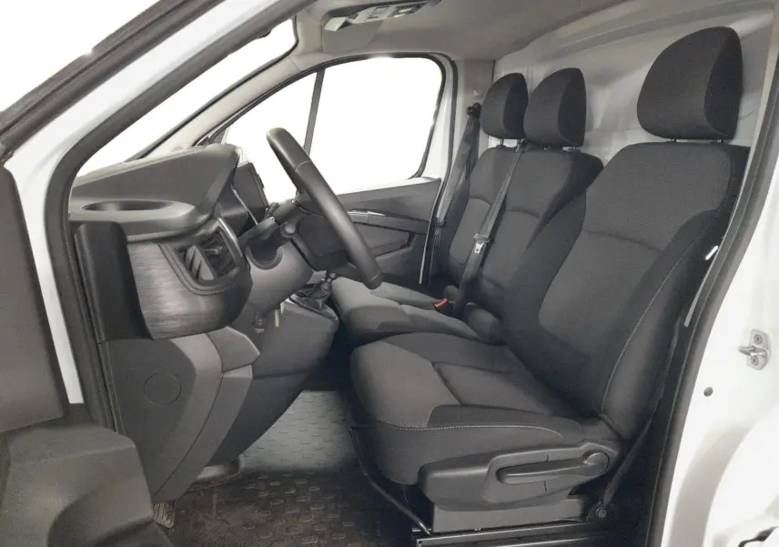 Vue intérieure côté gauche du Renault Trafic Fourgon blanc minéral 2024, montrant les sièges tissu noirs et le tableau de bord.