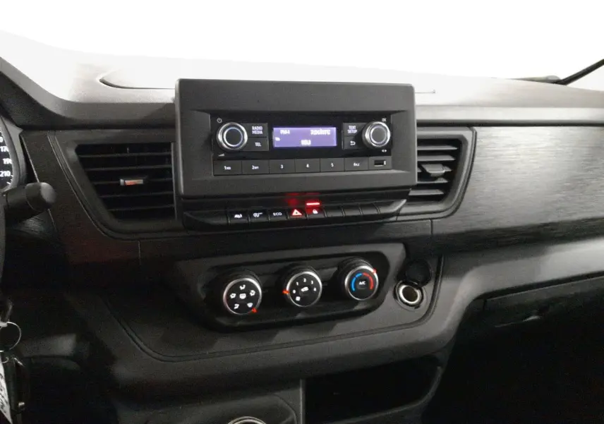 Tableau de bord du Renault Trafic Fourgon 2024, vue centrée sur la console avec radio, climatisation et levier de vitesses.