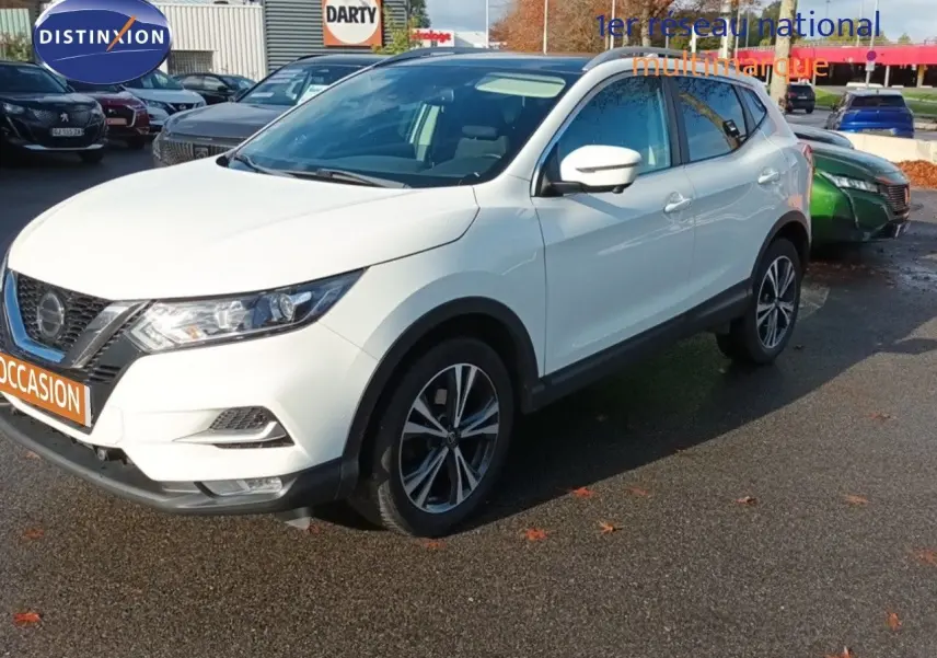 Nissan Qashqai blanc en 3/4 avant droit, avec jantes alliage bicolores et calandre distinctive noire.