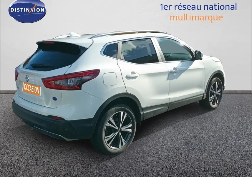 Nissan Qashqai blanc vue 3/4 arrière droit, avec jantes alliage bicolores et vitres teintées.