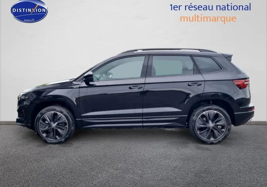 Profil côté gauche d'un Skoda Karoq noir 2025 avec jantes alu et barres de toit visibles sur fond neutre.