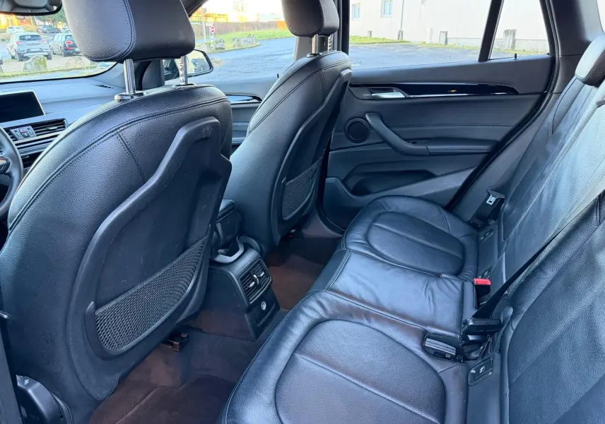 Vue intérieure arrière côté droit du BMW X1 18D M Sport 2018, sièges en cuir noir et console centrale avec aérateurs.