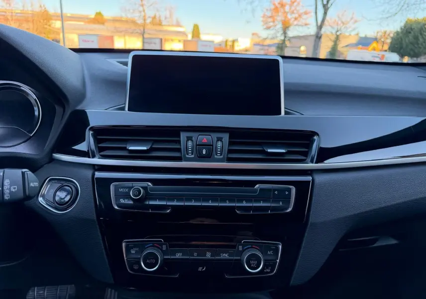 Vue intérieure centrée sur la console centrale du BMW X1 18D M Sport 2018 avec écran tactile et commandes de climatisation.