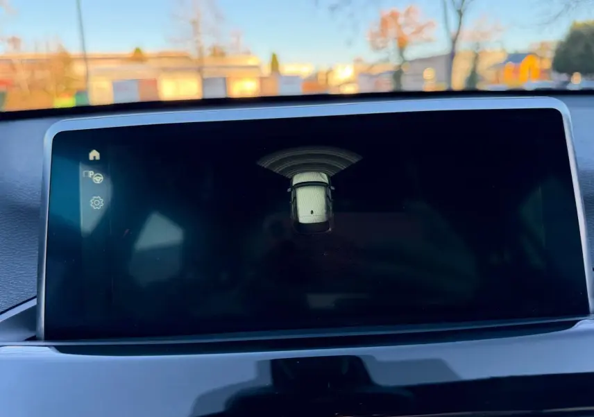 Écran central du BMW X1 18D 2018 montrant l’alerte de proximité avec vue stylisée du véhicule en blanc.