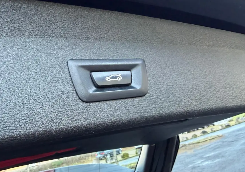 Bouton d'ouverture électrique du hayon sur la garniture intérieure noire du coffre d'un BMW X1 noir métal.