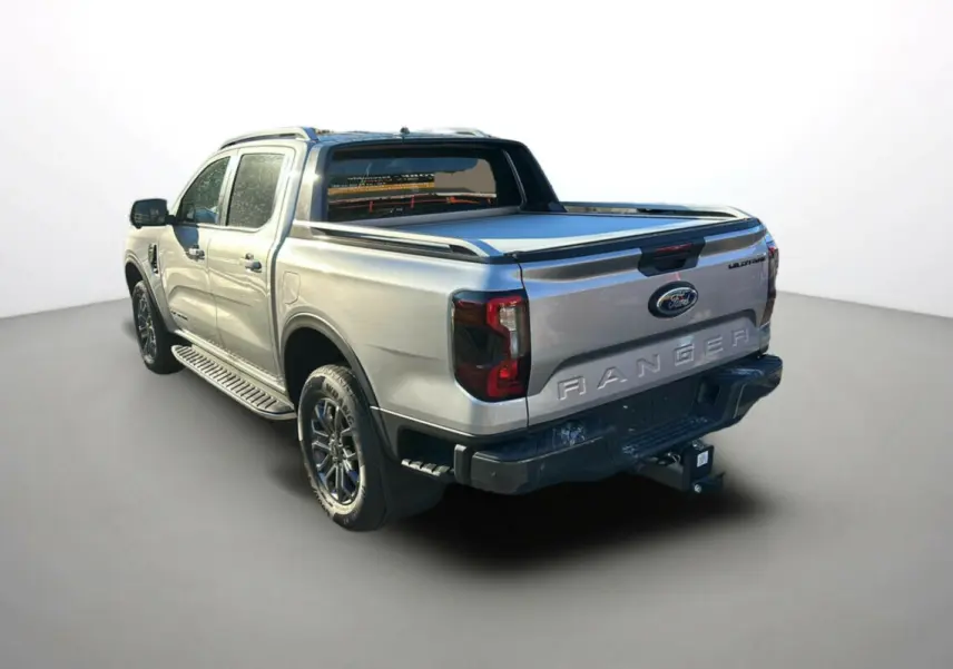 Ford Ranger 2.0 205 Wildtrak Plus gris iconic, vue 3/4 arrière droit avec attelage et bac de benne fermé.