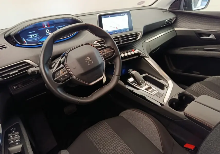 Intérieur Peugeot 5008 vu côté conducteur, tableau de bord moderne avec écran tactile et volant cuir noir.