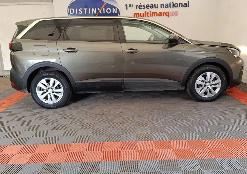 Profil droit d'un Peugeot 5008 gris foncé 2020 avec jantes alliage et vitres teintées, stationné en intérieur.