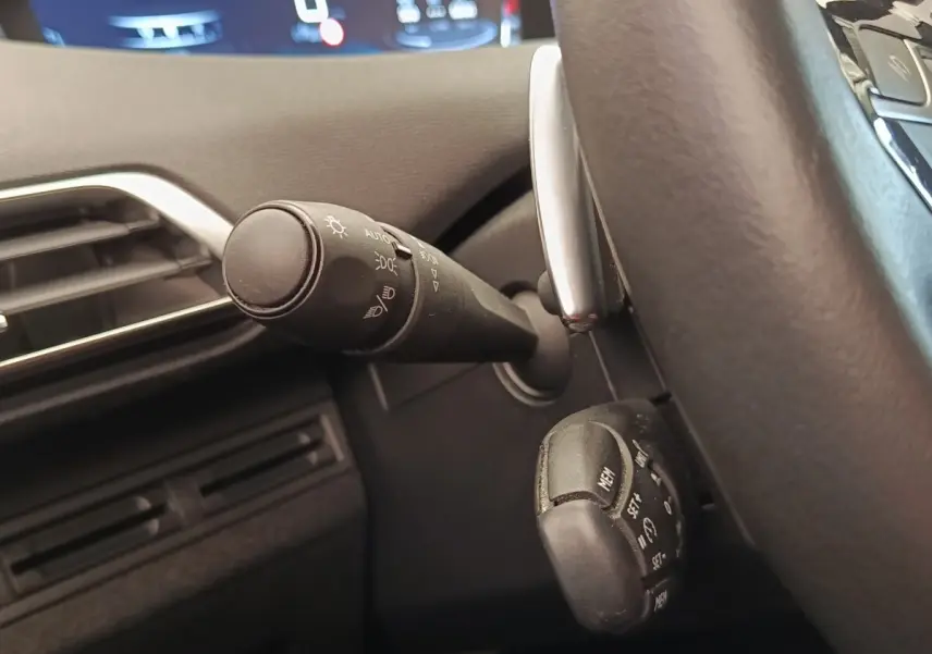 Gros plan sur la commande des phares et du régulateur de vitesse côté gauche du volant d’un Peugeot 5008 gris foncé 2020.